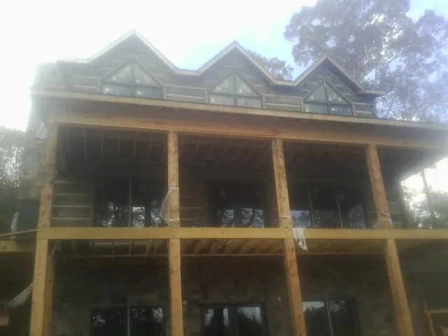 Dormers and porch framing on a large log home under construction — Roof Coating work by our crew in Egan