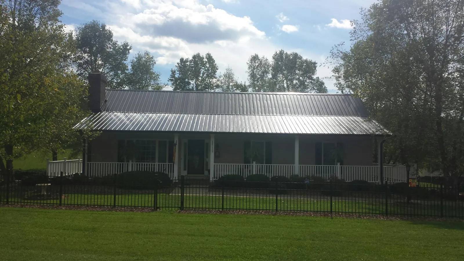 Gray metal roof on a brick ranch with a full width front porch — Gutter Guard Installation work by our crew in Egan